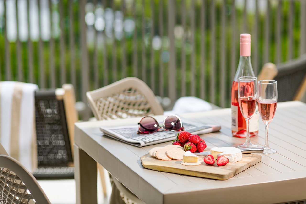 Balcony table set with a cheese board, strawberries and a bottle of rosé