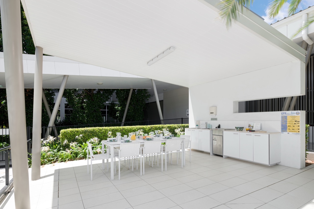 Covered BBQ pavilion with outdoor kitchen and a long dining table