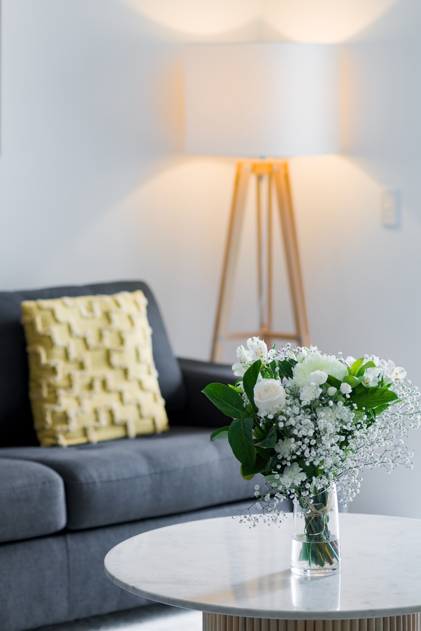 Fresh white flowers in a vase on a marble side table beside the living-room sofa