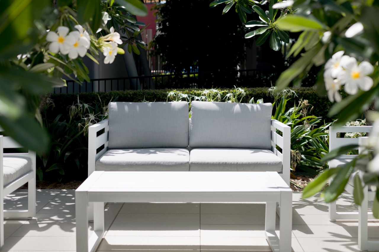 Outdoor garden lounge with white furniture under a frangipani tree