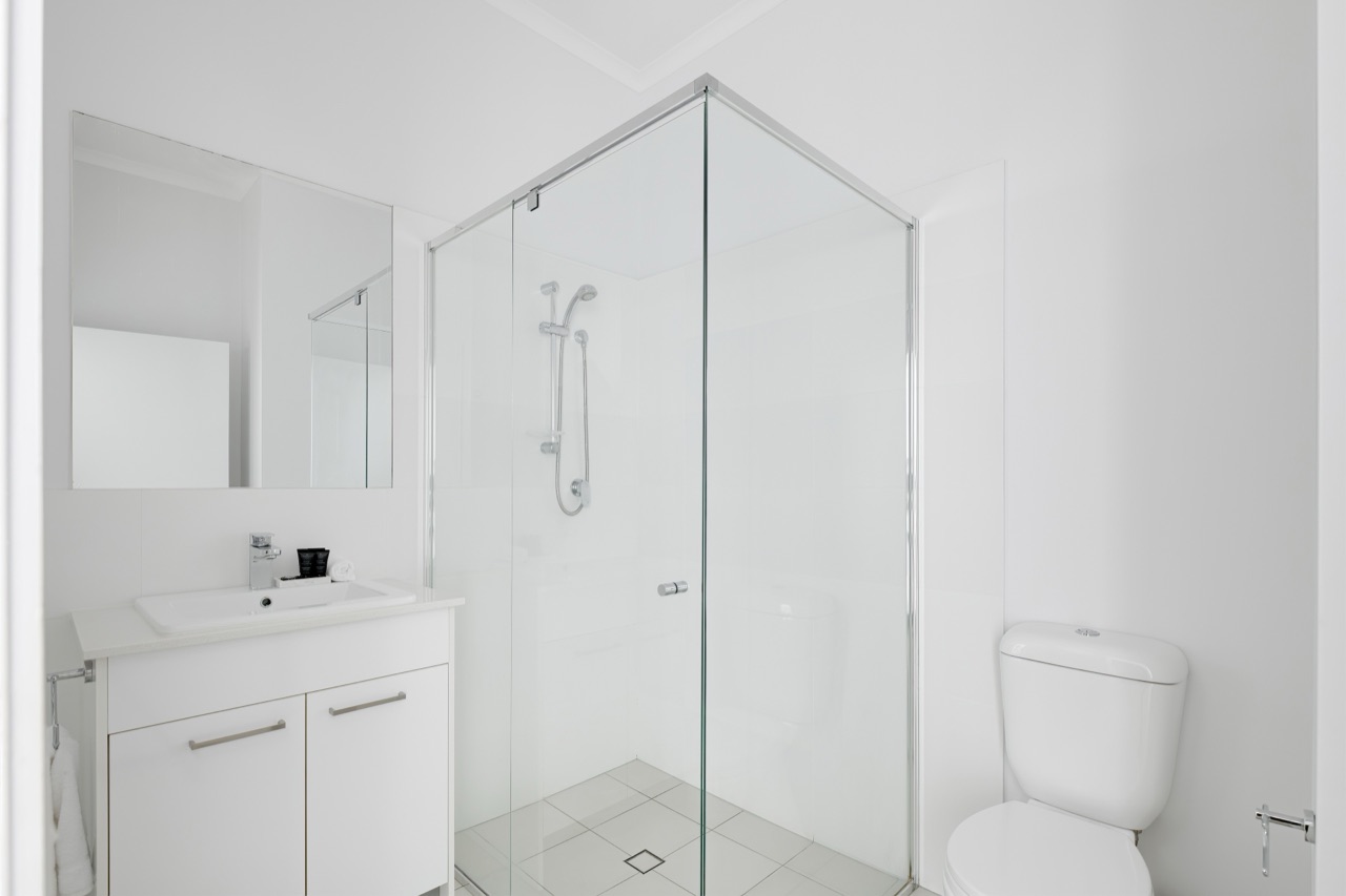 Main bathroom with vanity, corner glass shower and toilet