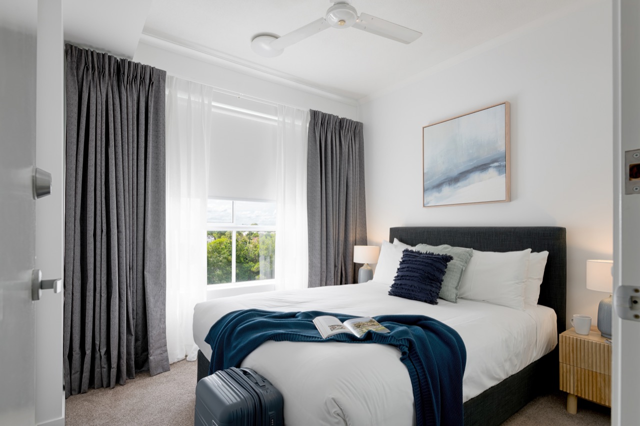 Master bedroom with queen bed, luggage rack and natural side light