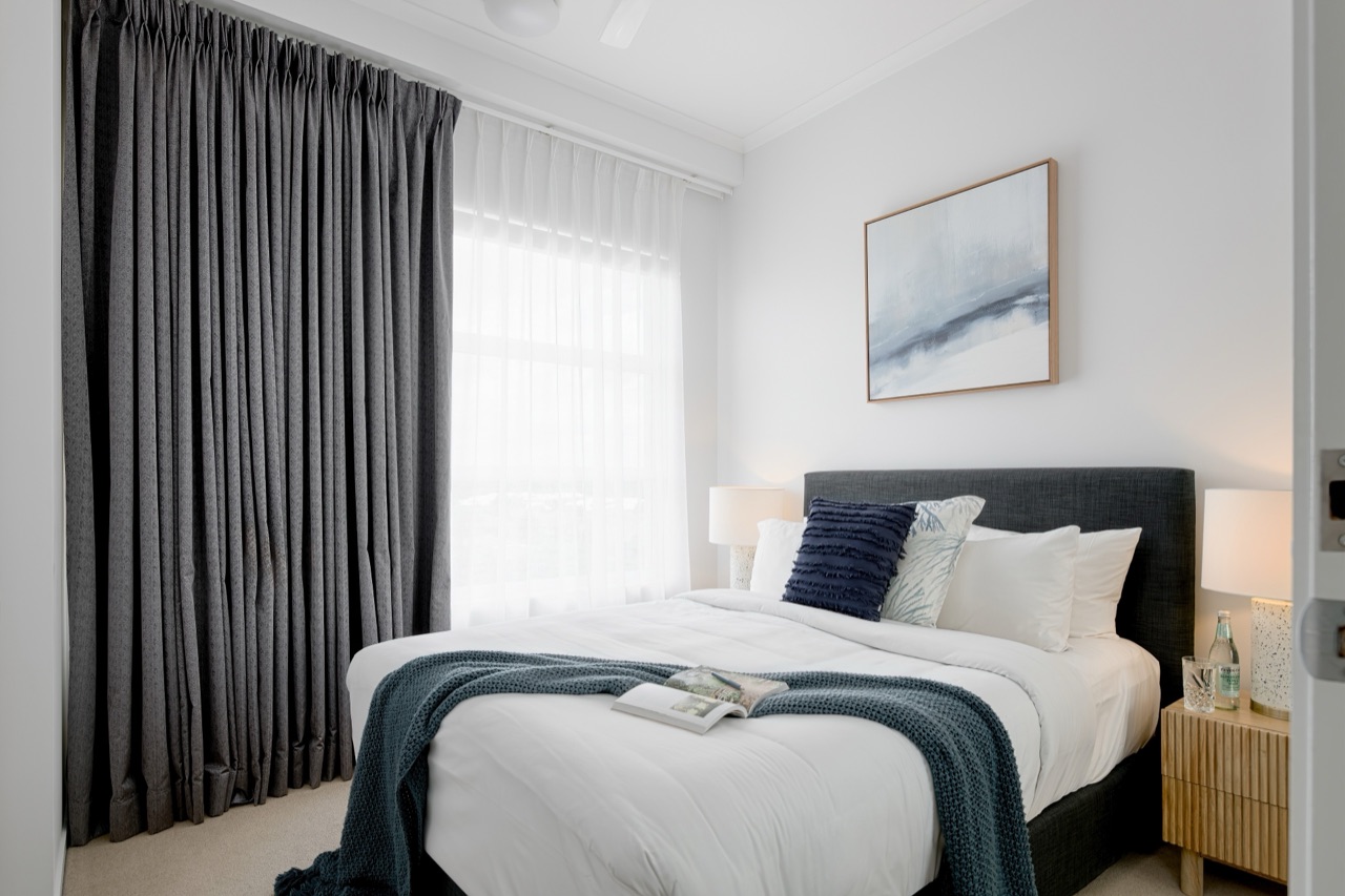 Second bedroom with queen bed, navy cushions and restful styling