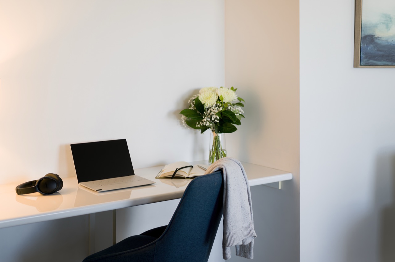 In-room workspace with built-in desk, laptop and flowers